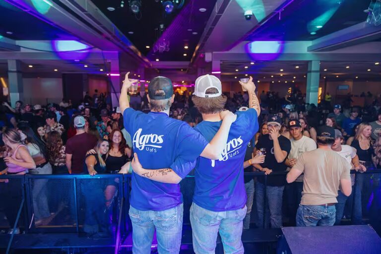 Two U of S Agros members in front of large crowd at Ag Bag Drag event
