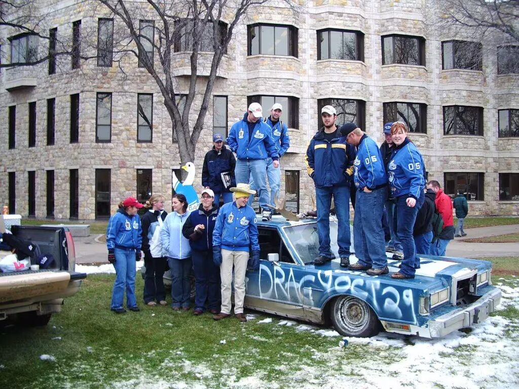 Tradition of Ag Bag Drag Students on Car with Goose mascot 2004